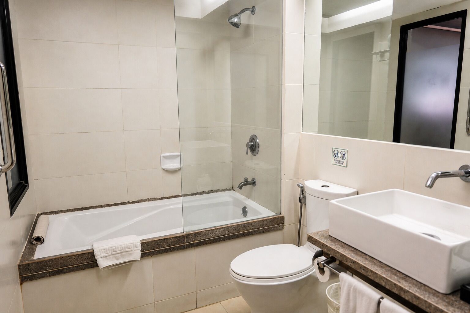 Une salle de bain avec une douche à parois de verre, des toilettes et un lavabo.