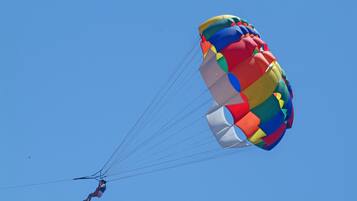 A person skydiving with a colorful parachute against a clear blue sky.