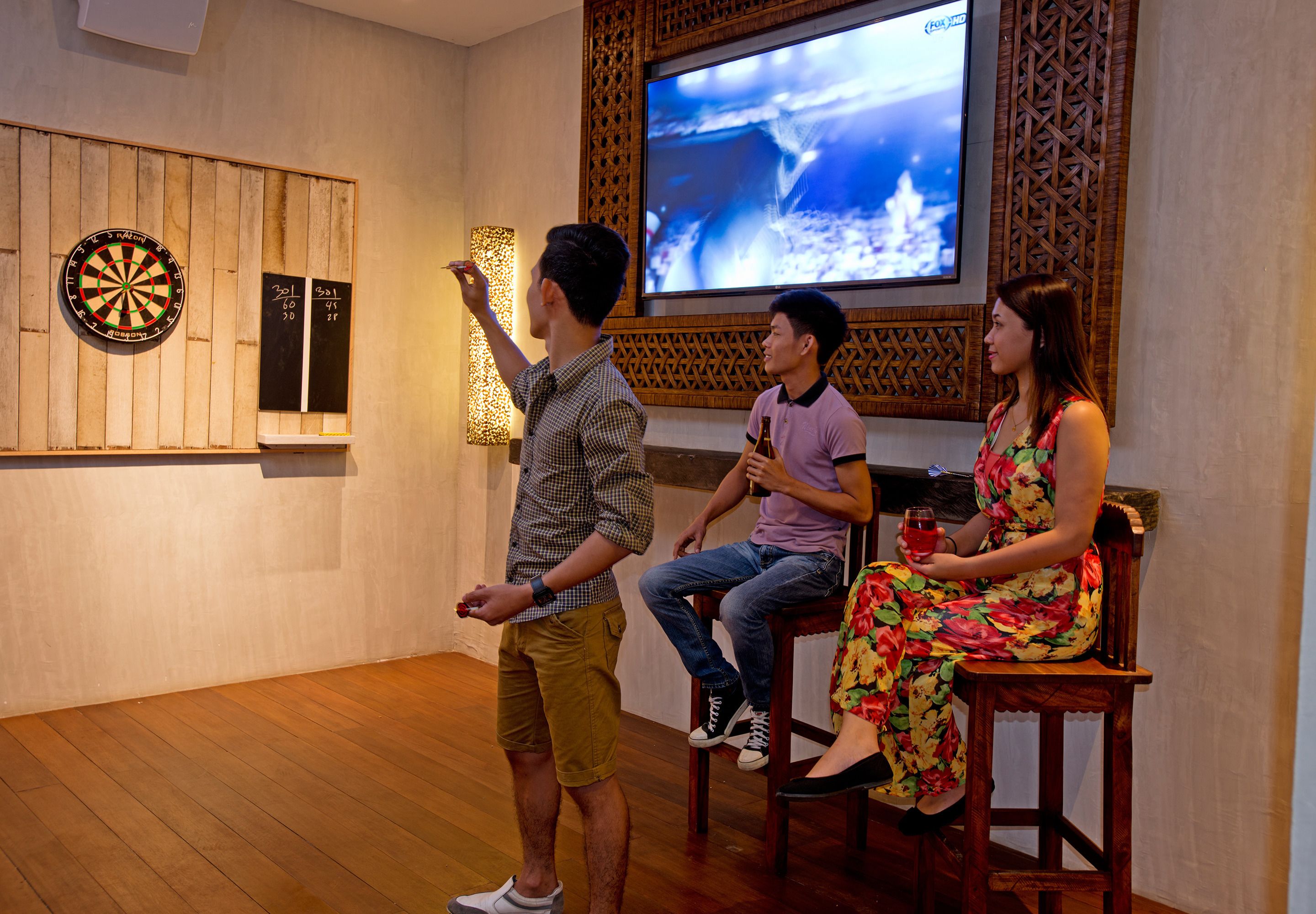 A room with a dartboard, a television, and wooden paneling.