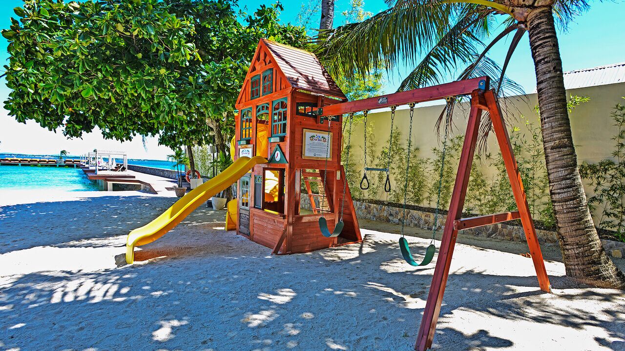A beach playground with a swing set and a slide.