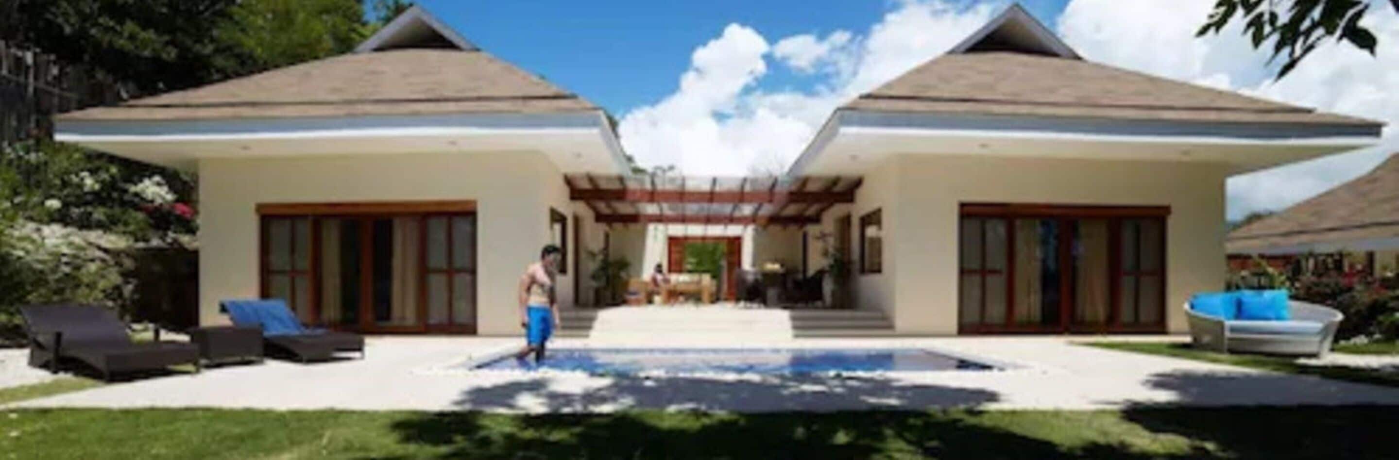 A two-story house with a swimming pool in the center, surrounded by a garden.