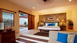 Un dormitorio con una cama, un sofá, un aparador de madera y un ventanal grande.