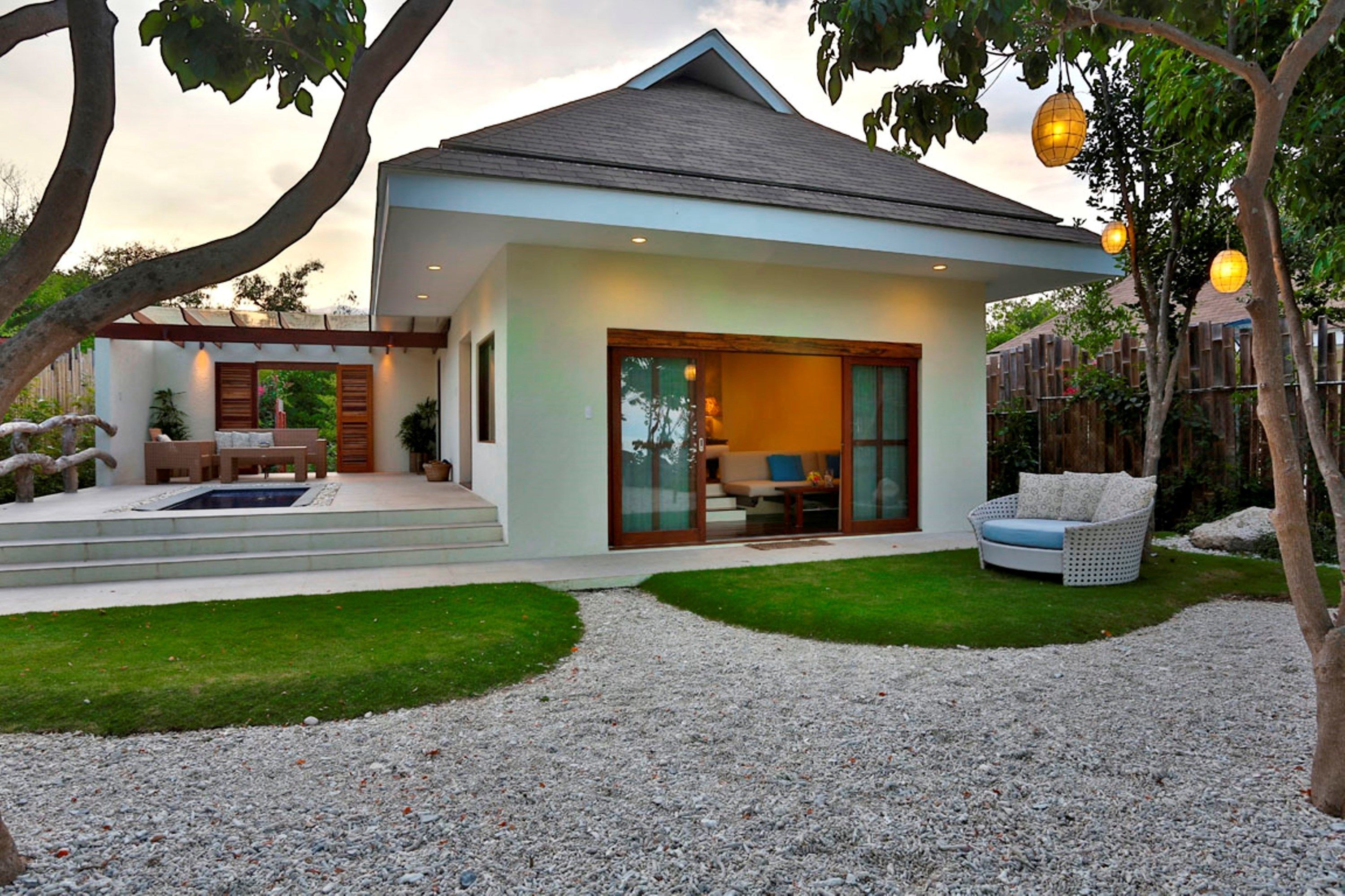 A modern house with a patio, outdoor seating, and a well-maintained lawn.