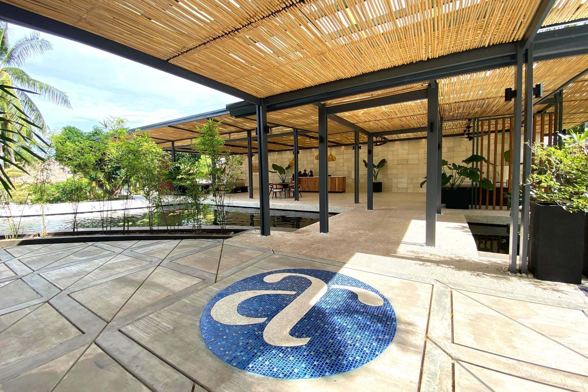 An outdoor area with a pool, covered seating, and a reception desk.