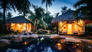A resort with two thatched-roof cabins, a swimming pool, and tropical vegetation. - Atmosphere Resorts & Spa (Dauin)