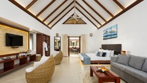 A spacious living area with a high ceiling, a large flat-screen TV, wicker furniture, a grey sofa, and a wooden coffee table. - Atmosphere Resorts & Spa (Dauin)