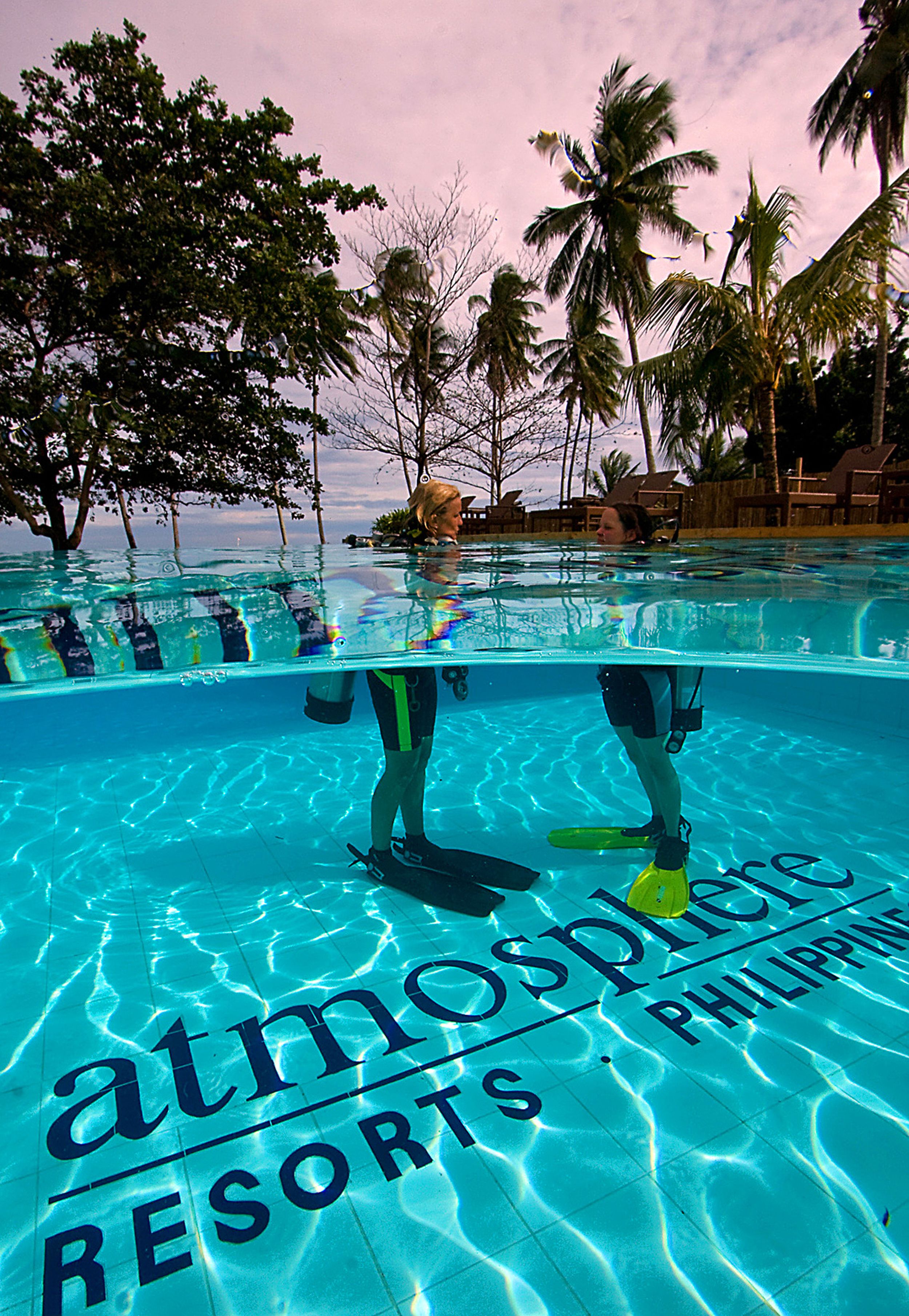 An underwater view of a swimming pool with the words "atmosphere resorts" and "philippines" visible on the pool's surface.