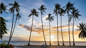 A beach with white lounge chairs and a clear view of the sunset over the ocean. - Atmosphere Resorts & Spa (Dauin)