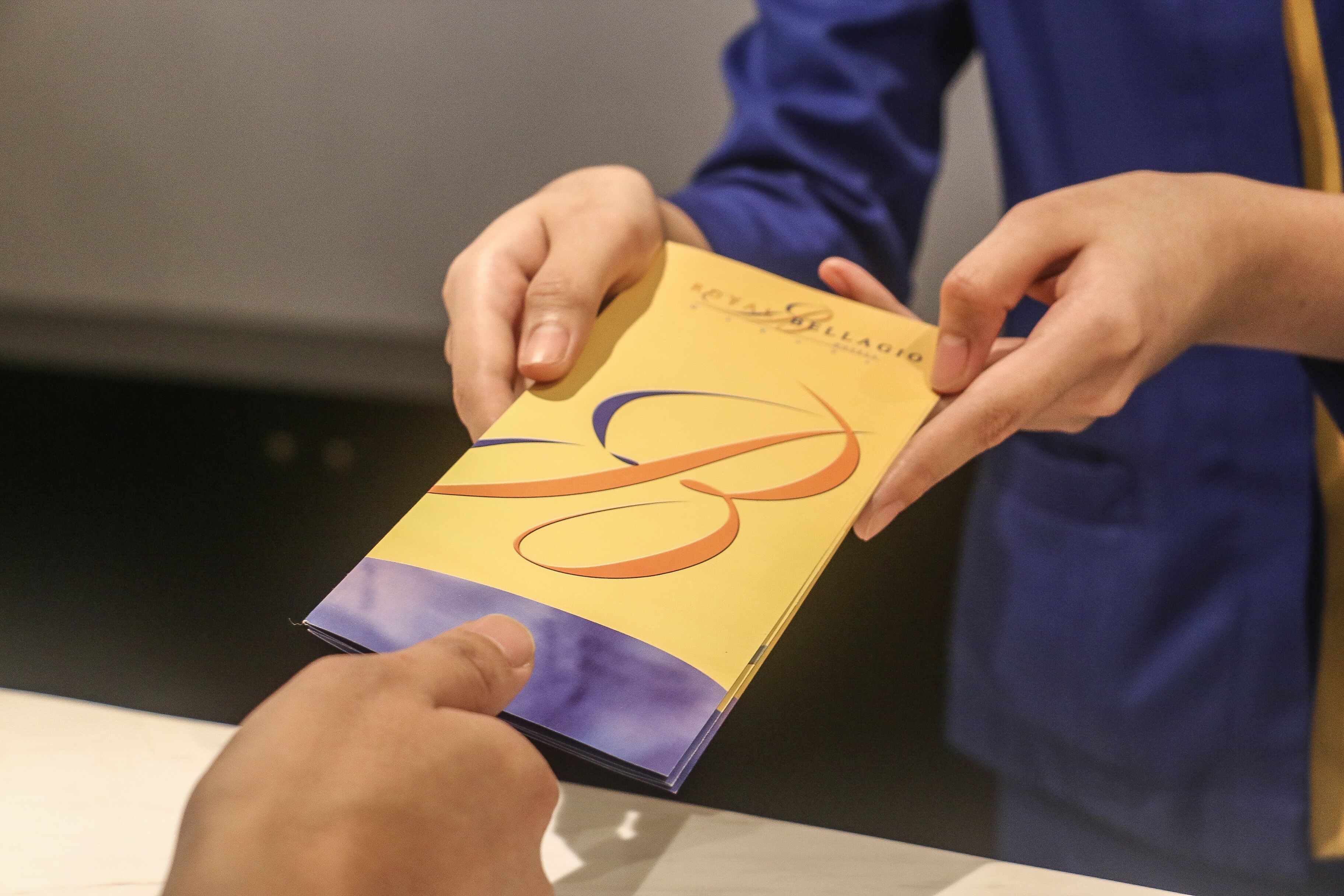 A person holding a yellow booklet with a purple and orange design.