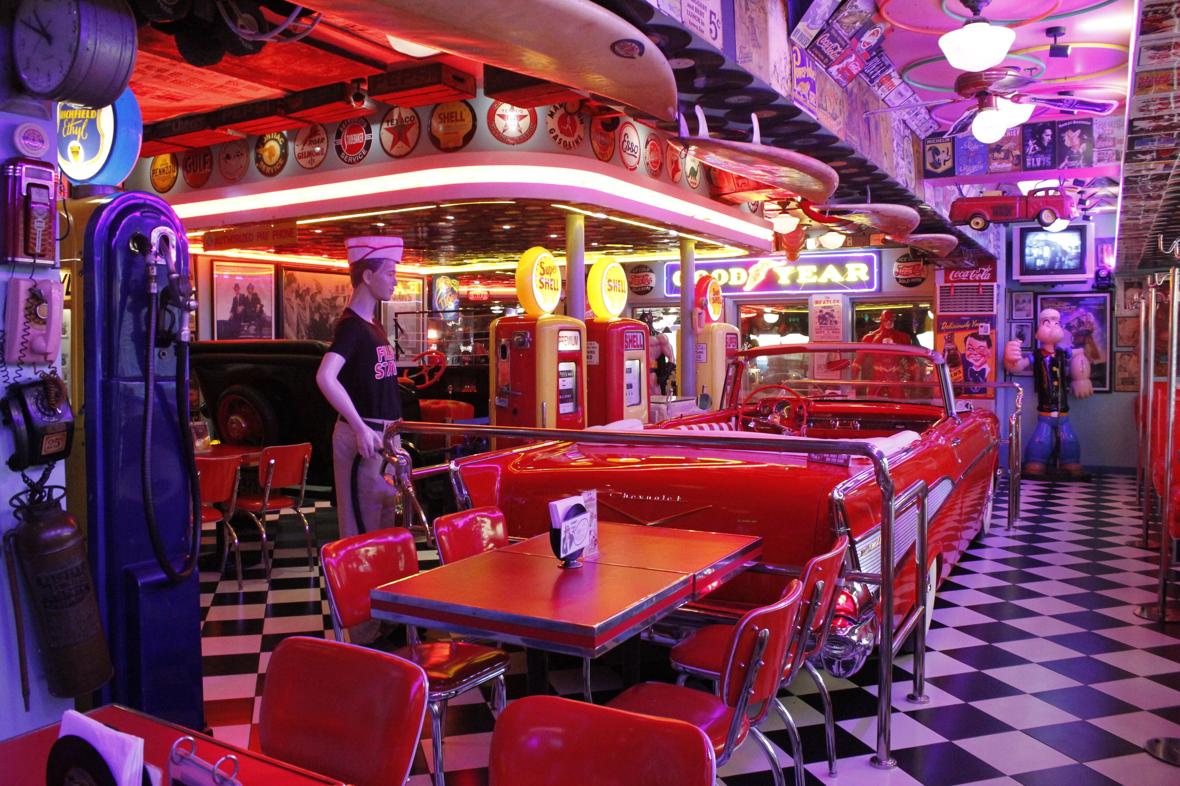 A retro diner with vintage cars, neon signs, and classic diner furniture.