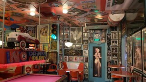 A retro-themed bar with a pool table, neon signs, and vintage posters. - Royal Bellagio Hotel (Makati)