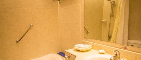 A bathroom with a bathtub, two sinks, a toilet, and a mirror.