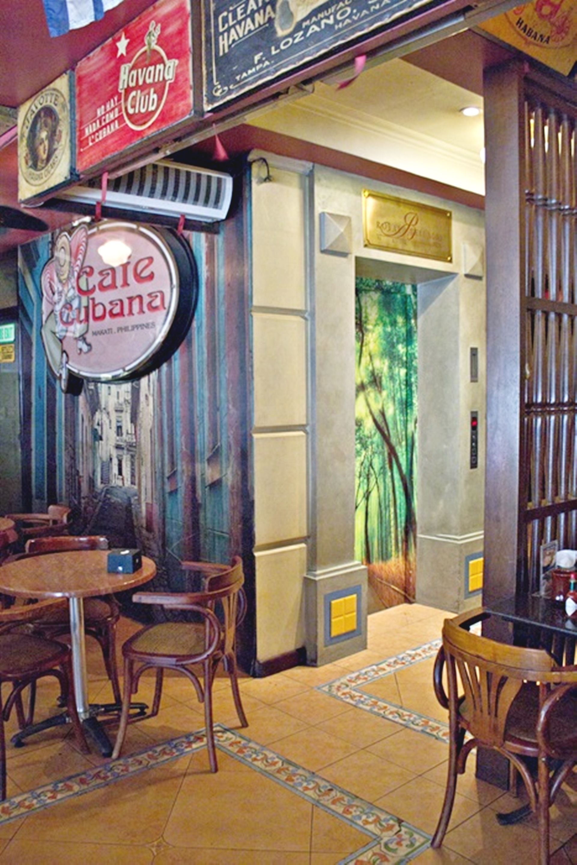 Ein Restaurantinneres mit Holztischen und -stühlen, einer Wandmalerei und einem Schild für 'Cafe Cubana'.