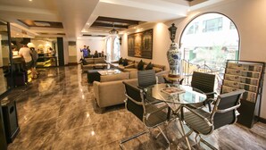 A spacious lobby with a glass table and chairs, a sofa area, and a large arched window. - Royal Bellagio Hotel (Makati)