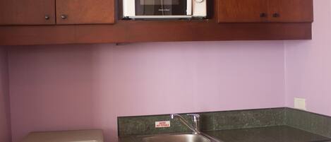 A kitchen with wooden cabinets, a microwave, a sink, and a refrigerator.