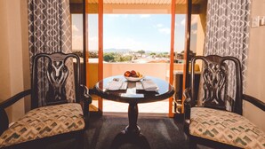 Una habitación con una mesa preparada para dos personas, vistas al exterior y cortinas estampadas.