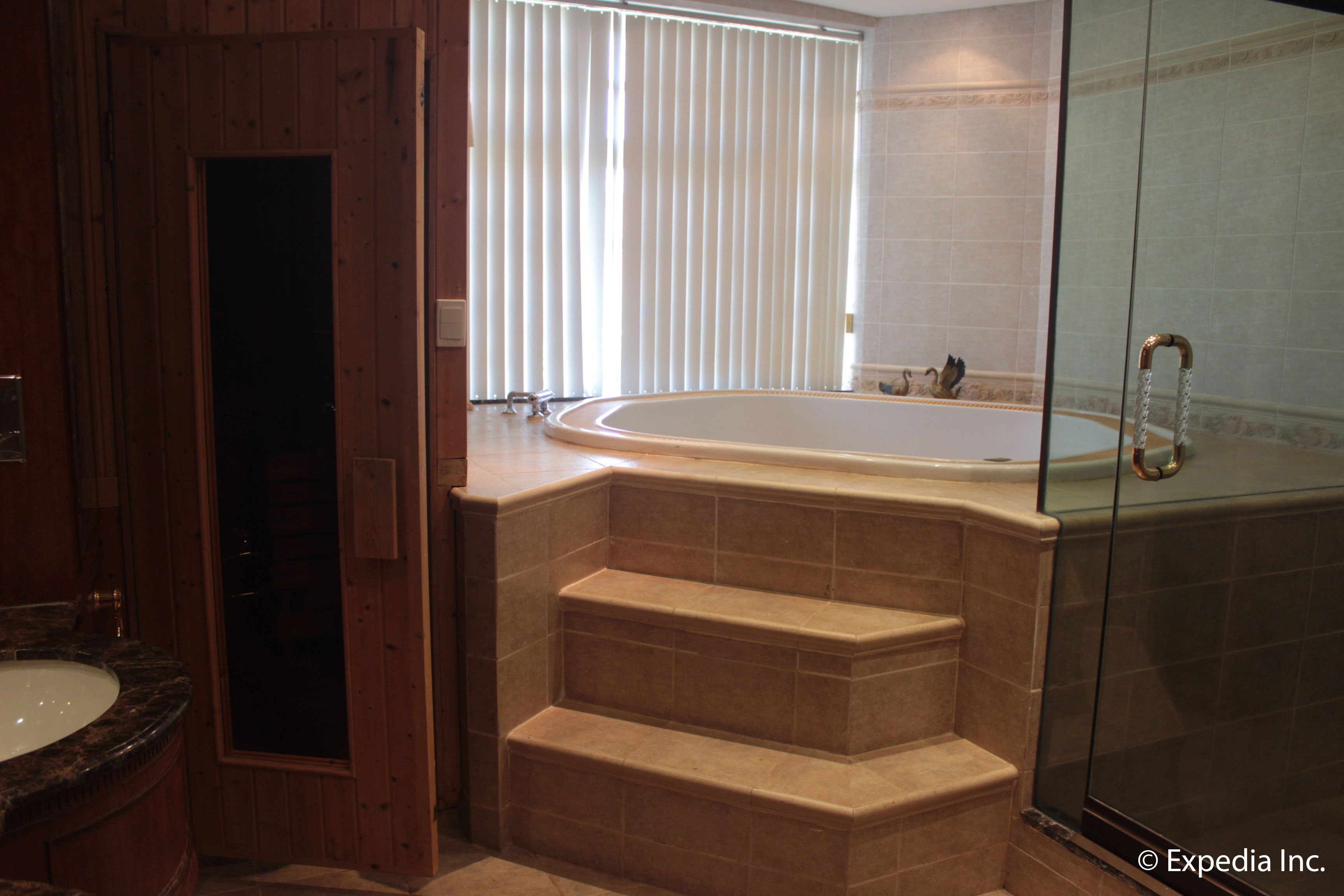A bathroom with a bathtub, a glass shower enclosure, and a wooden door.