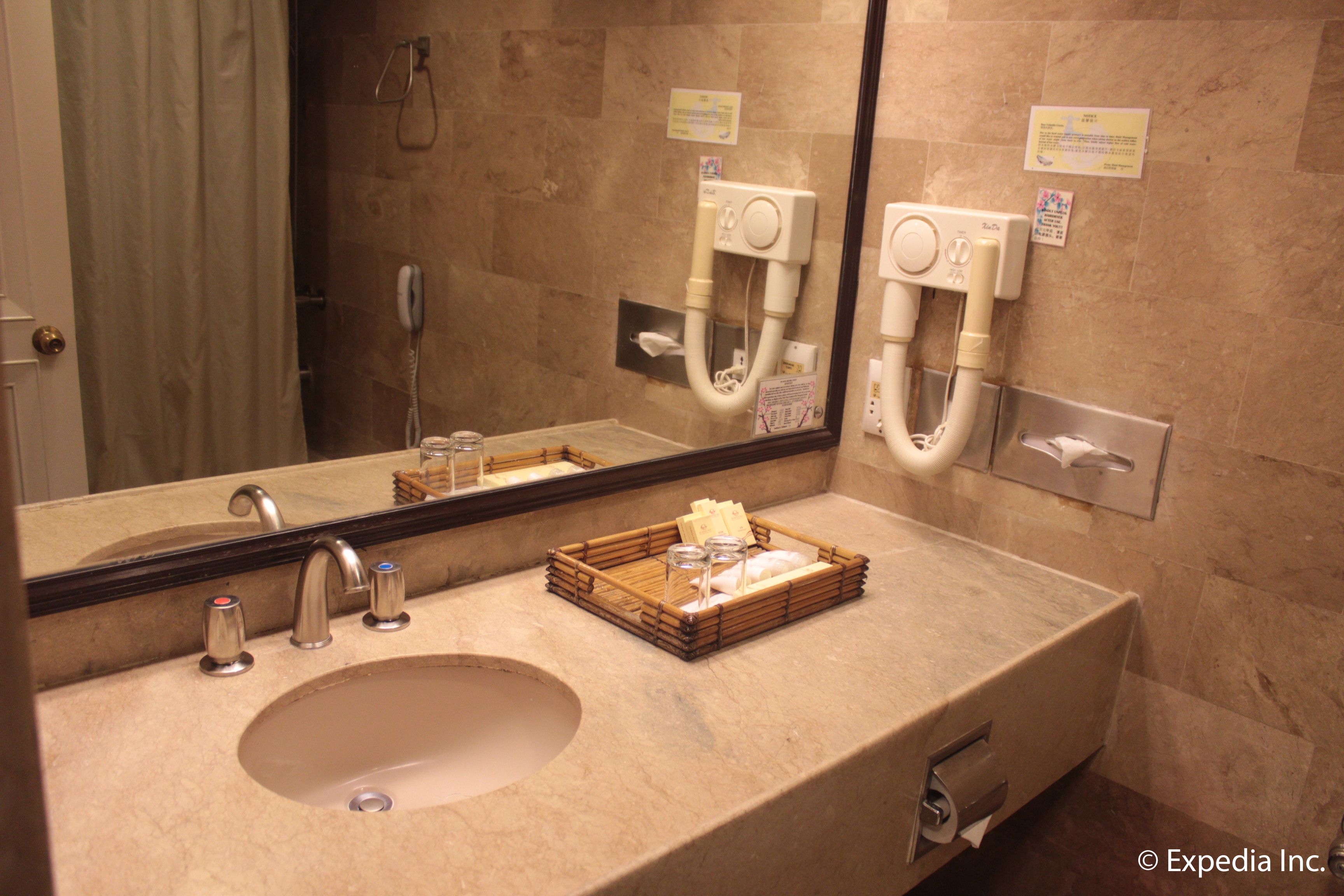 Un baño con lavamanos, espejo y dispensador de toallas.