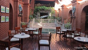 An indoor courtyard with brick walls, a stone staircase, and multiple tables and chairs. - Fort Ilocandia Resort Hotel (Laoag)