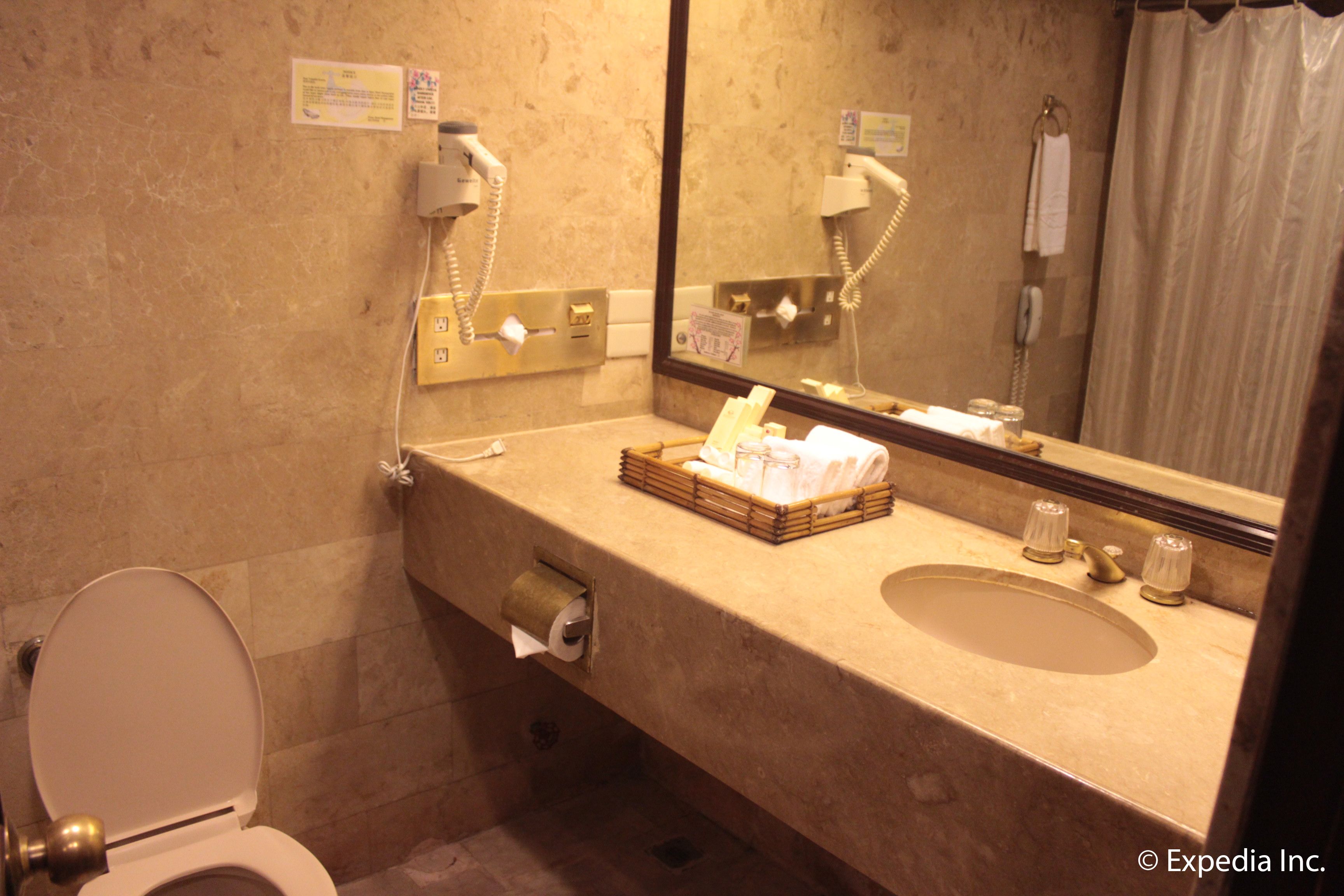A bathroom with a toilet, sink, and mirror.