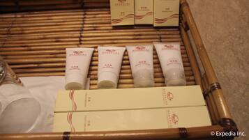 A set of toiletries arranged on a bamboo mat, including shampoo, body lotion, and a toothbrush.