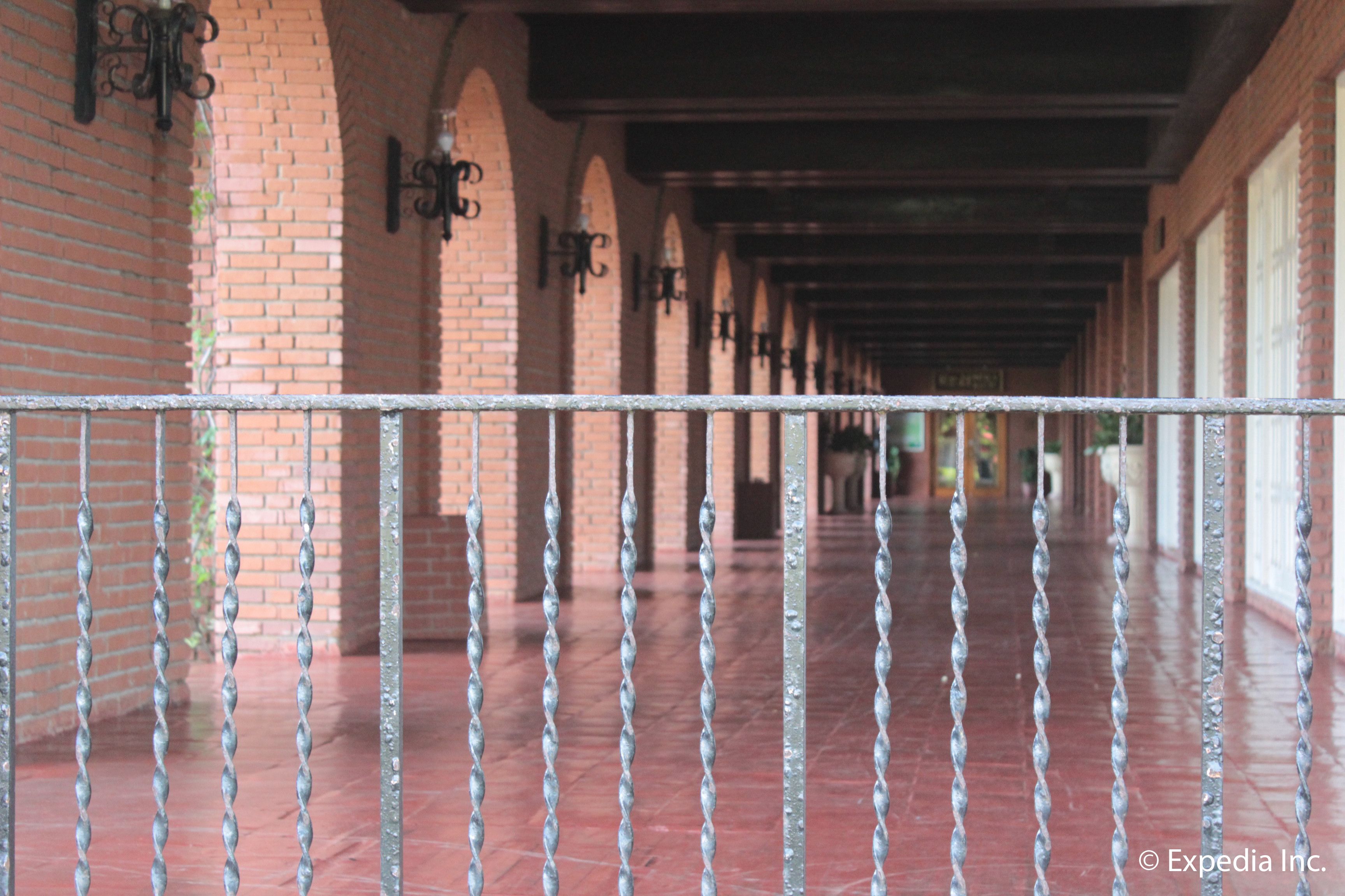 A covered corridor with brick walls and metal railings.