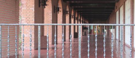 A covered corridor with brick walls and metal railings.