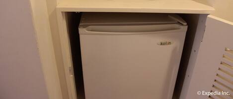A kitchenette with a refrigerator, two white cups, and a coffee maker on a white countertop.