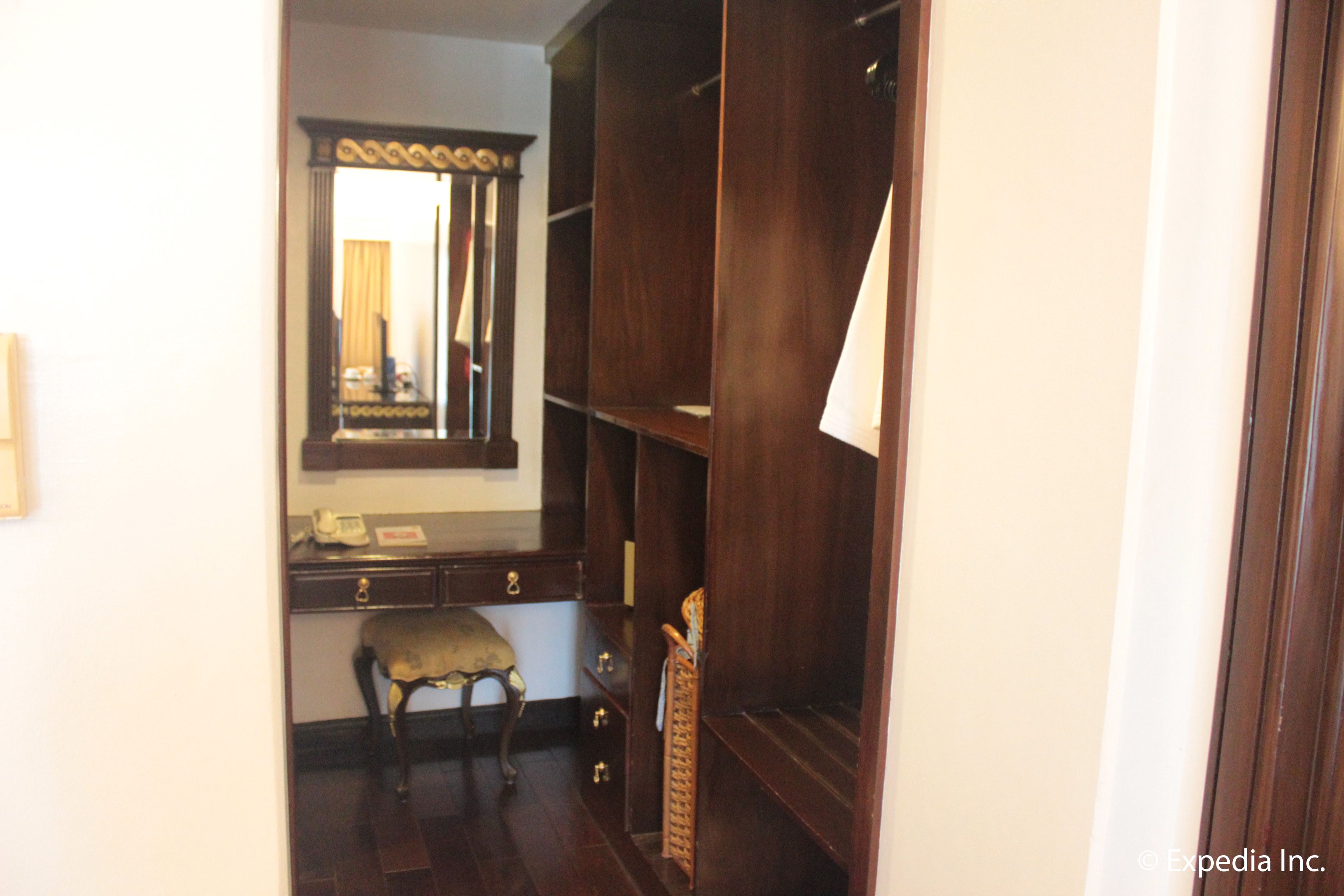 A room with a wooden desk, a chair, a mirror, and a wardrobe.