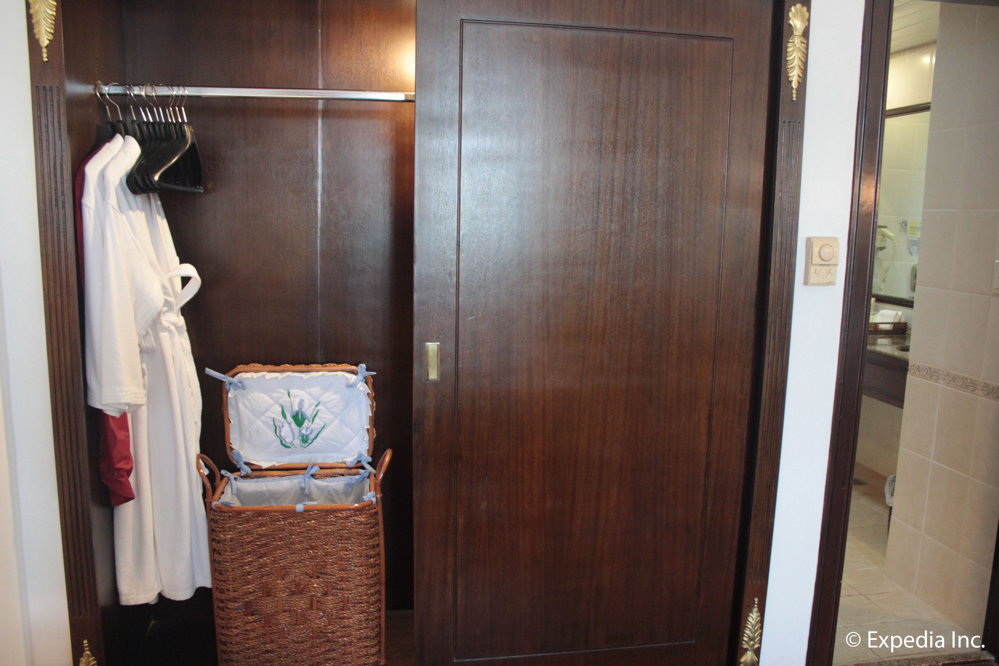 A wooden wardrobe with a mirror, a hanging rack with clothes, and a wicker basket.