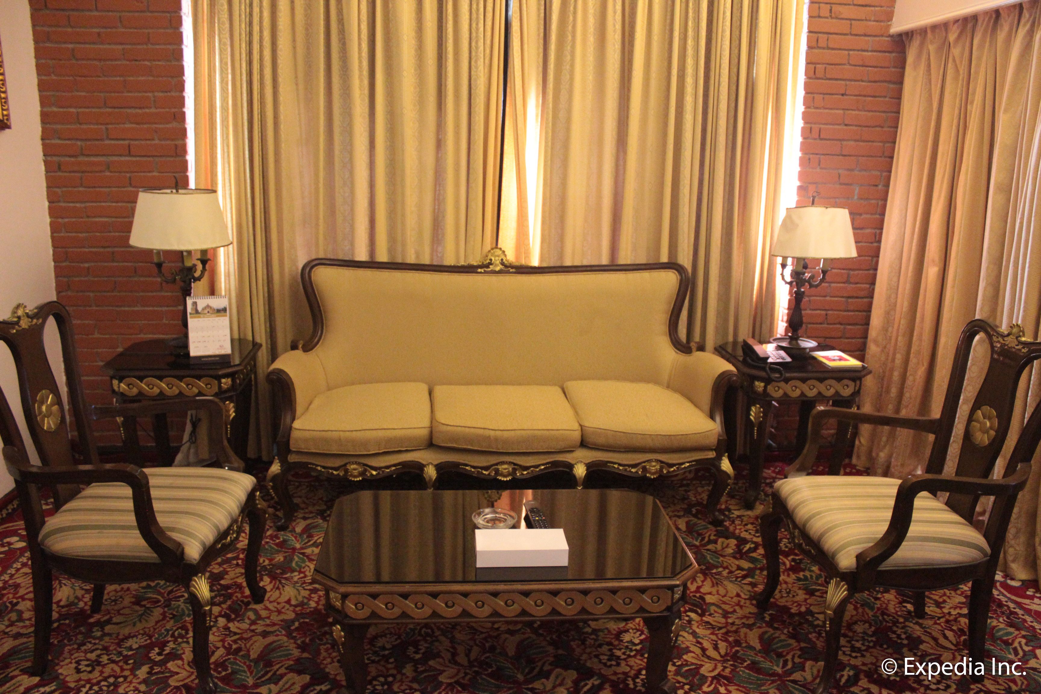 Habitación de hotel con un conjunto de sofá, dos sillones, una mesa de centro y dos lámparas.