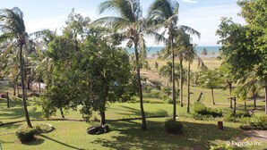 A tropical landscape with palm trees, a golf course, and a view of the ocean. - Fort Ilocandia Resort Hotel (Laoag)