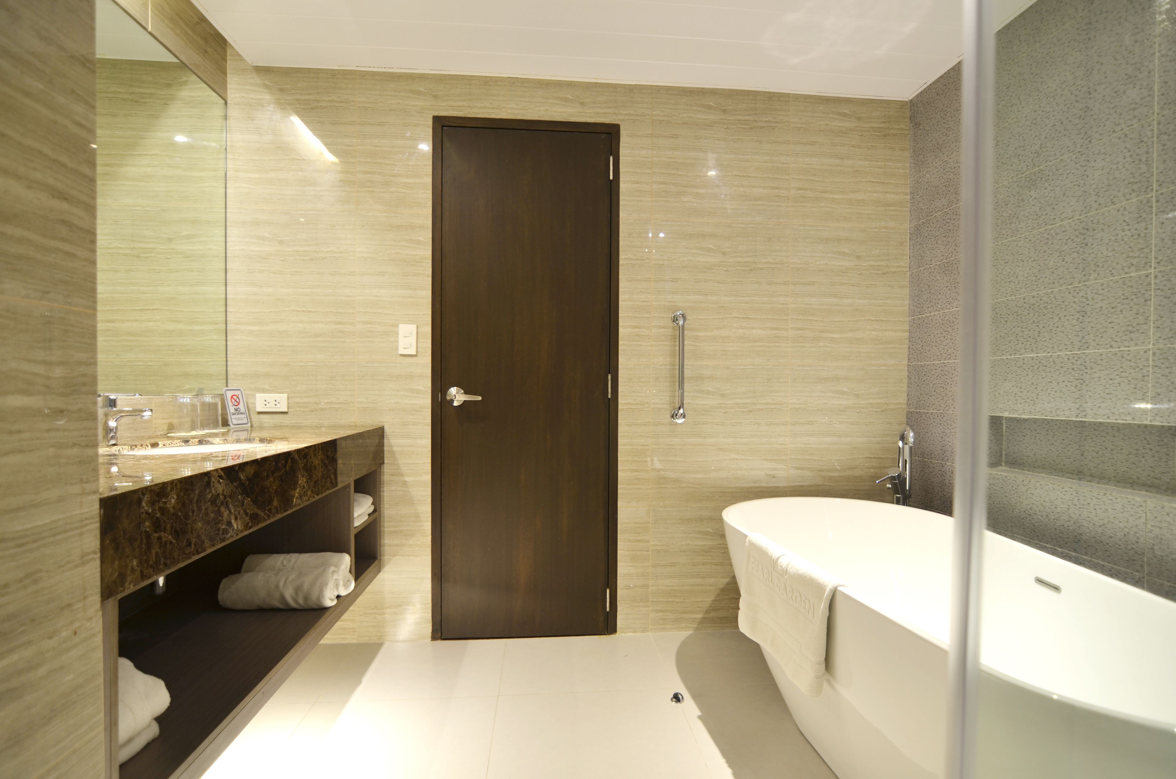 Une salle de bain moderne avec un meuble-lavabo en marbre, un grand miroir, une baignoire et une porte.
