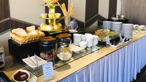 A buffet setup with various food items including bread, pastries, and condiments. - Pearl Garden Hotel (Manila)