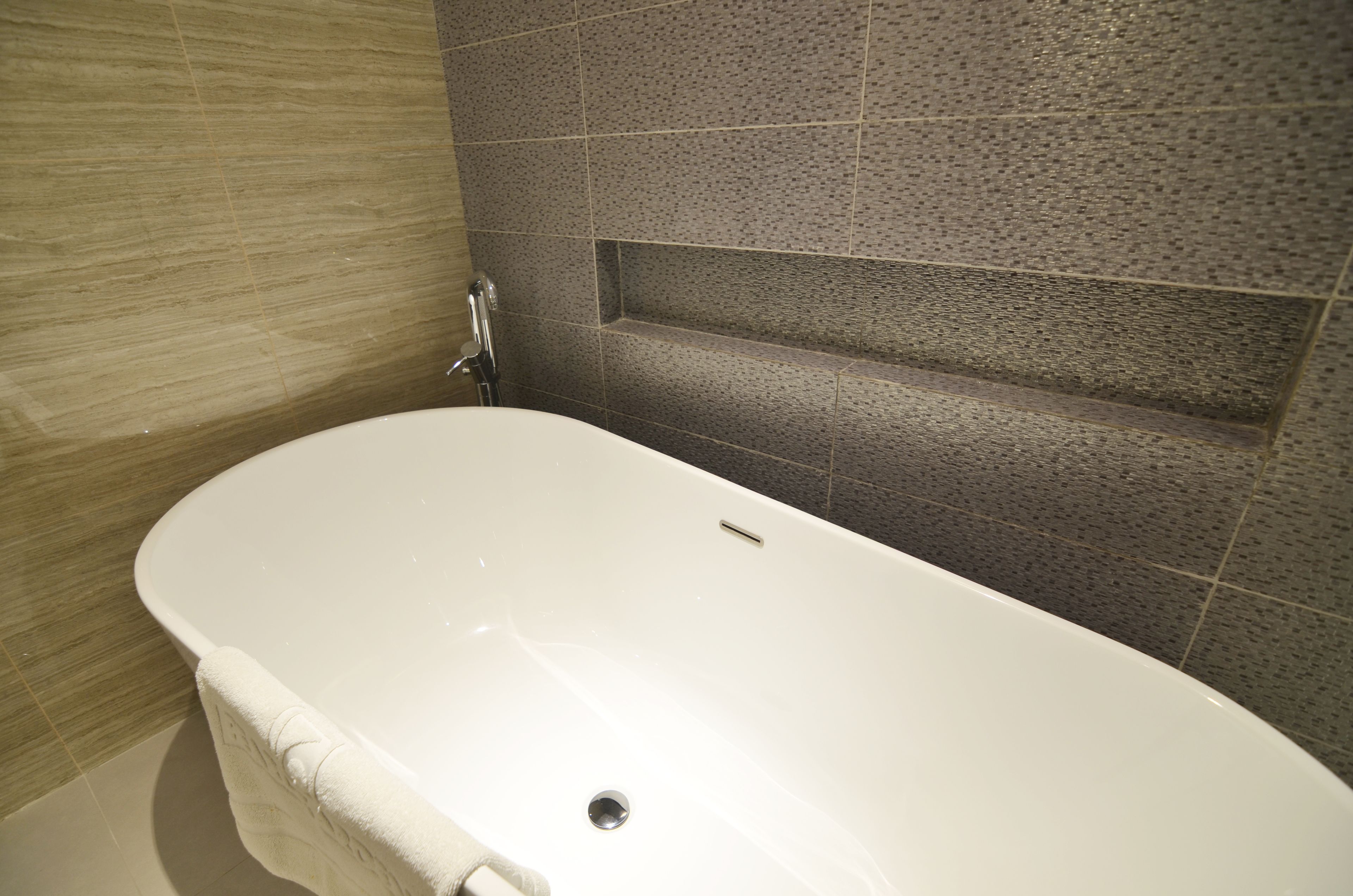 A bathroom with a white bathtub, a towel rack, and a shower area.