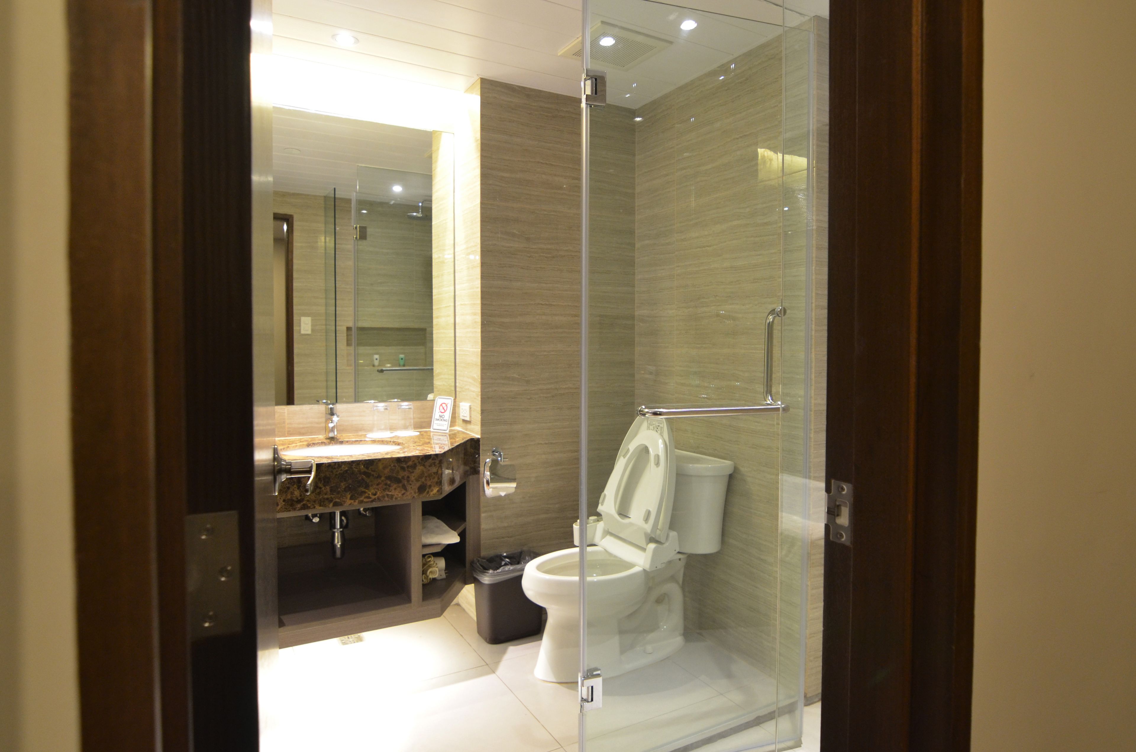 A modern bathroom with a glass-enclosed shower, a marble sink, and a toilet.