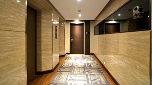 A modern hallway with a patterned floor, marble walls, and a wooden door at the end. - Pearl Garden Hotel (Manila)
