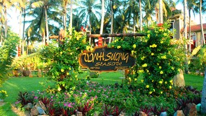 A sign for 'JUNHSUONG SEASIDE HOTEL & RESORT' surrounded by lush greenery and tropical plants. - Vinh Suong Seaside (Mui Ne)