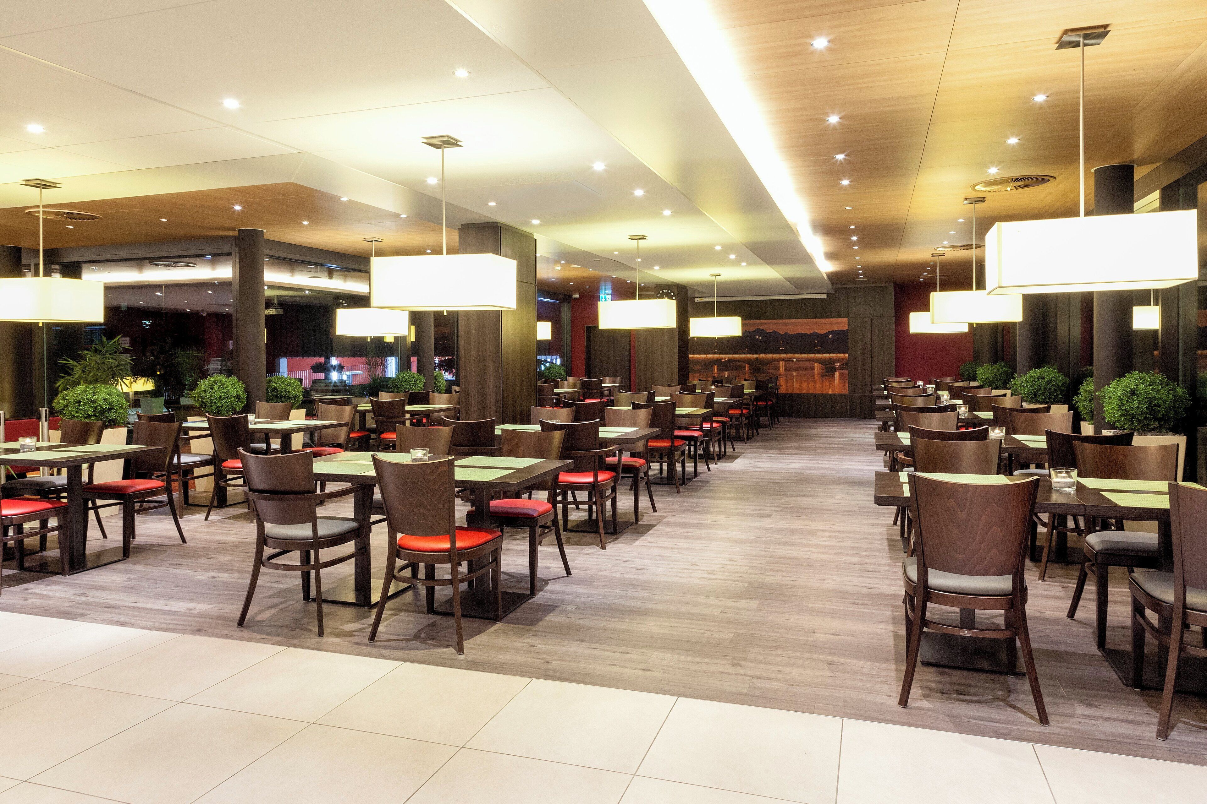 Un restaurante amplio con varias mesas y sillas, iluminación colgante y un diseño de interiores moderno.