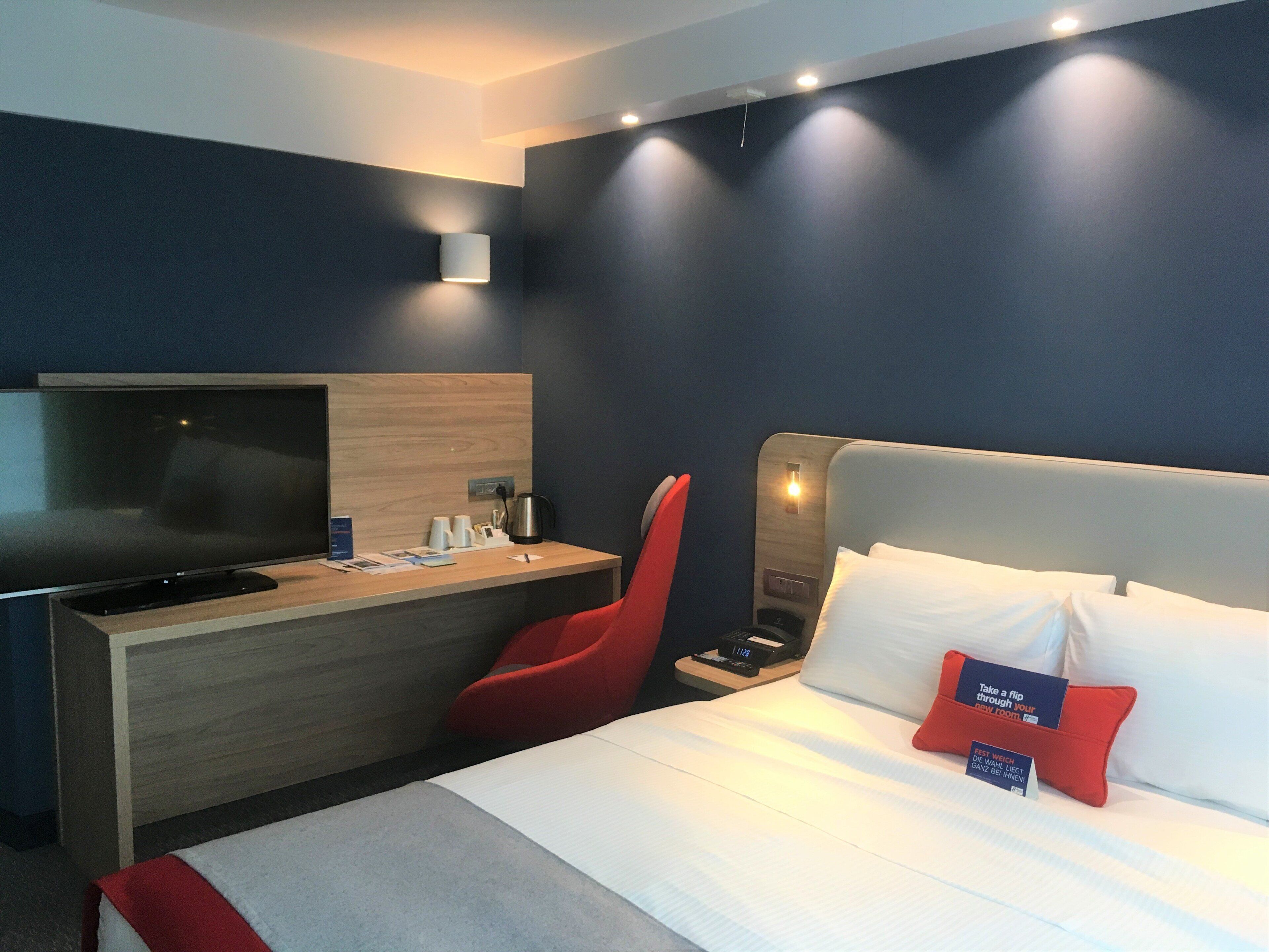 Une chambre d’hôtel avec un lit, un bureau, une chaise et un téléviseur.