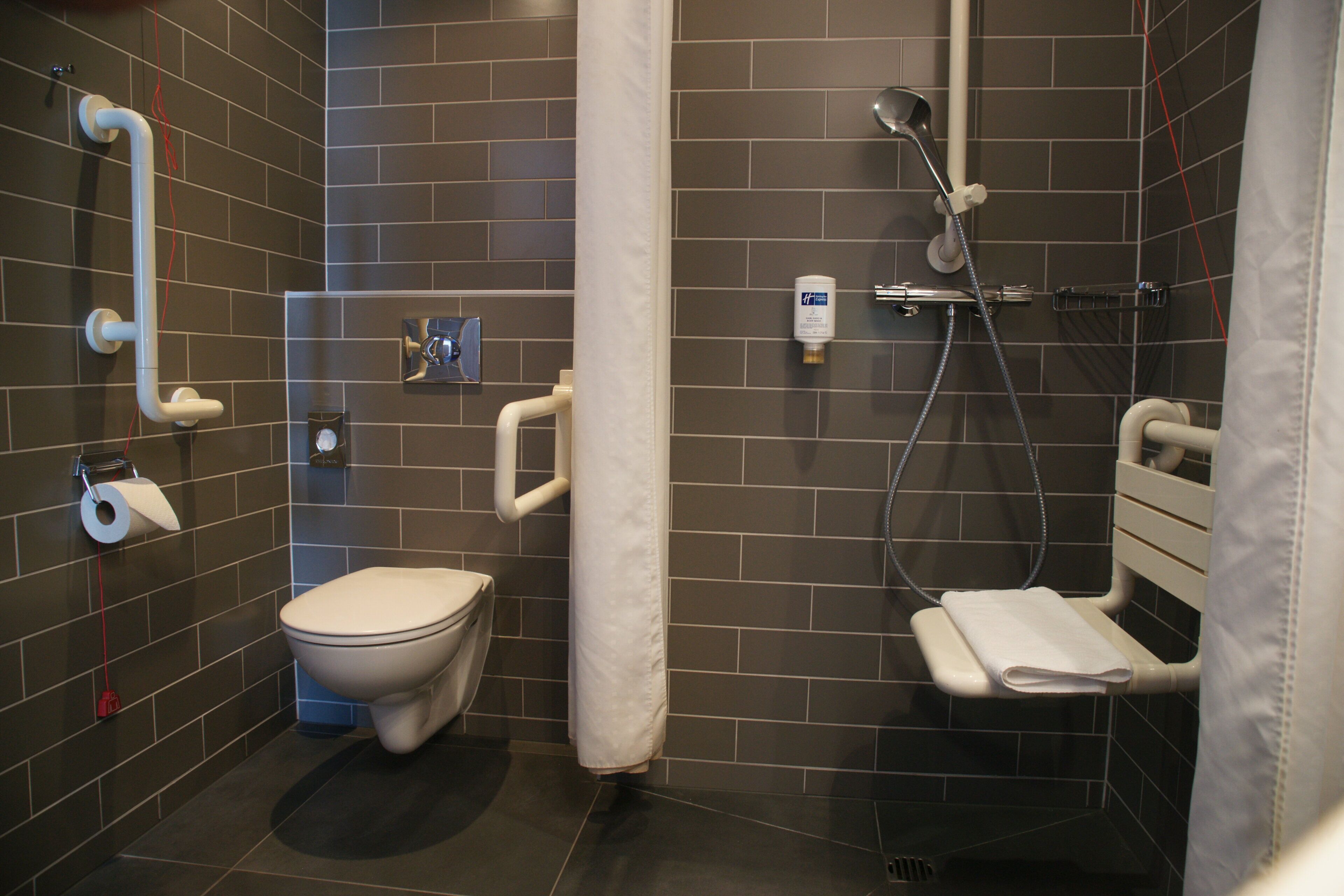 Un baño moderno con inodoro, ducha y secamanos.