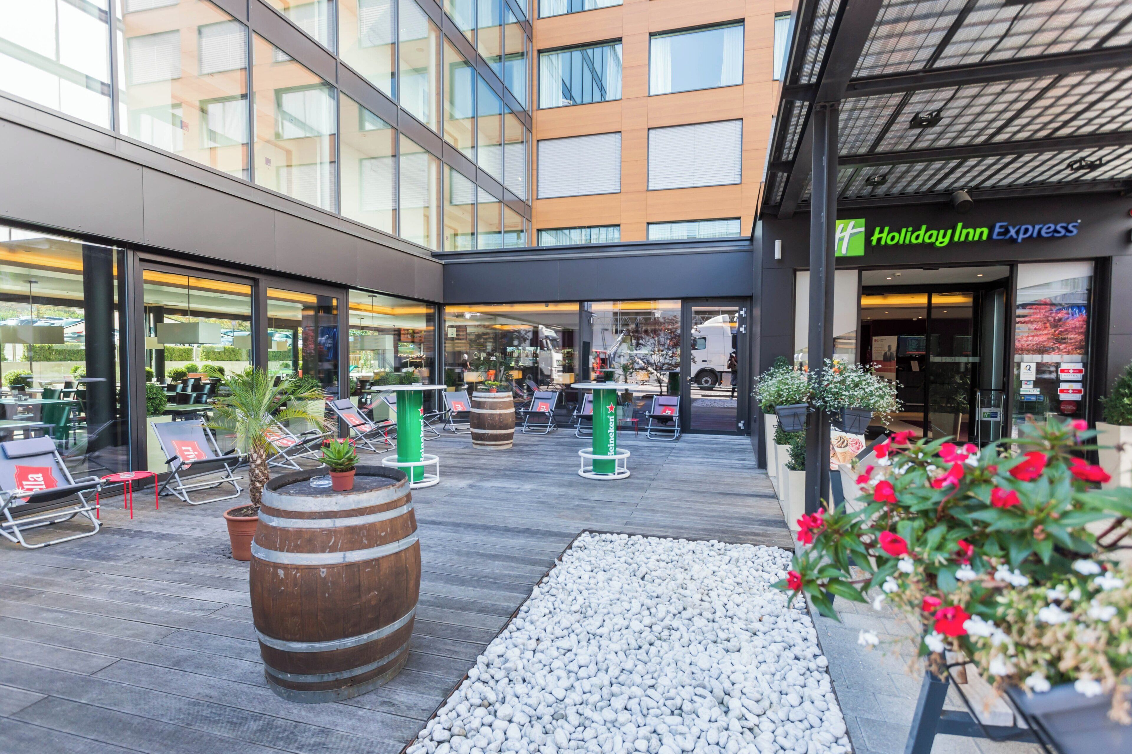 An outdoor seating area with tables and chairs, a decorative barrel, and a Holiday Inn Express sign.