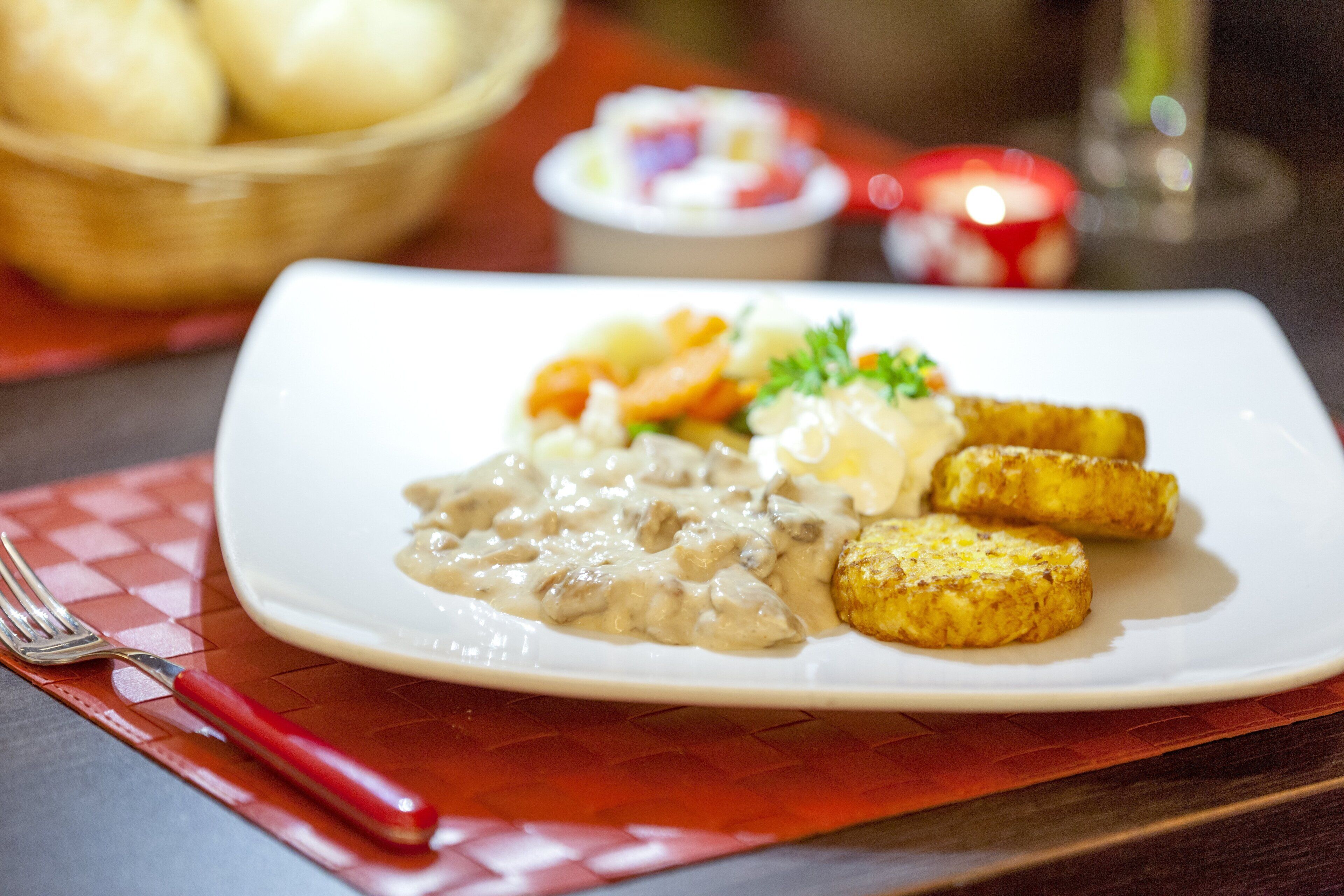 Un plato de comida con salsa cremosa, patatas asadas y verduras sobre un plato blanco.