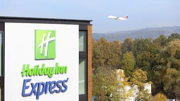Señal de Holiday Inn Express con vistas a un bosque y un avión al fondo.