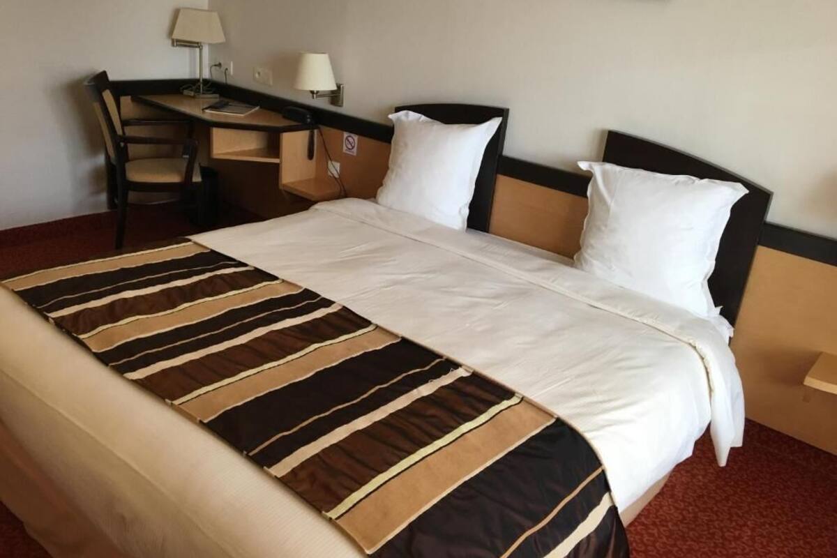 Una habitación de hotel con cama, escritorio y silla.
