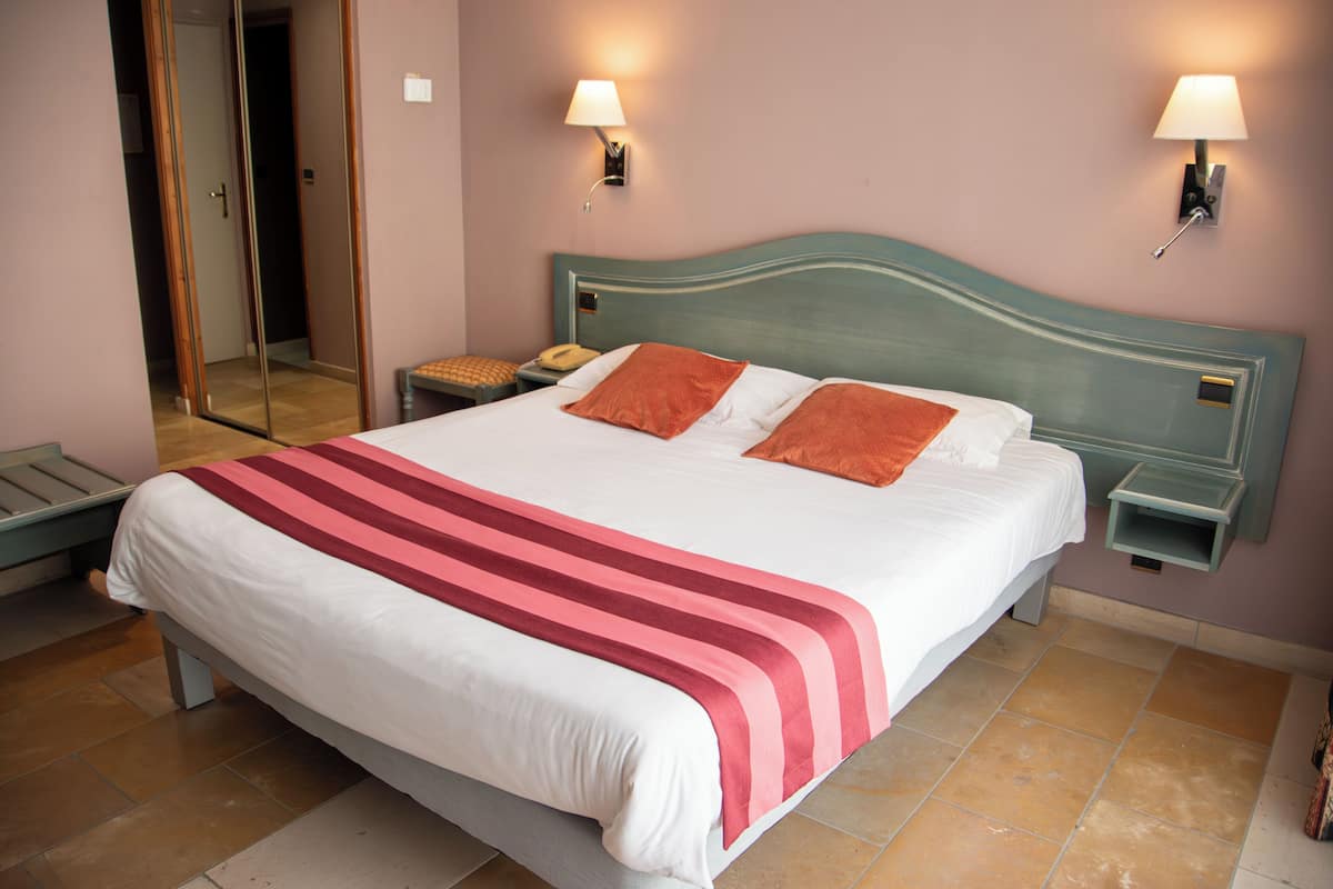 A neatly made bed with a striped bedspread, two bedside tables with lamps, and a large mirror on the wall.