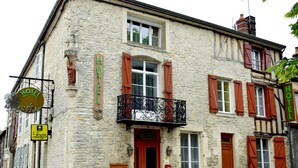 A stone building with a wooden door and a balcony with wrought iron railings.