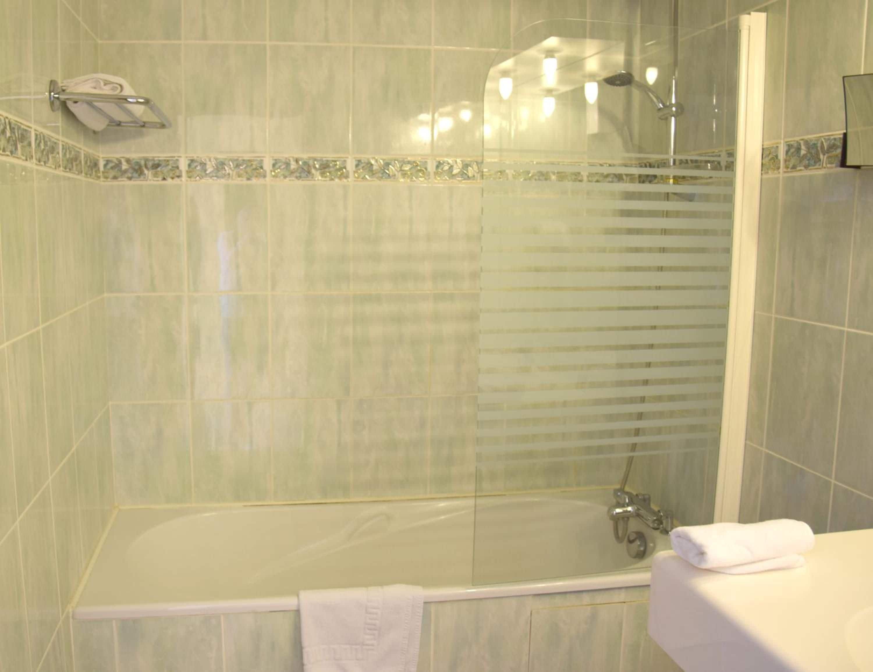 A bathroom with a glass-enclosed shower, a white bathtub, and a white sink.