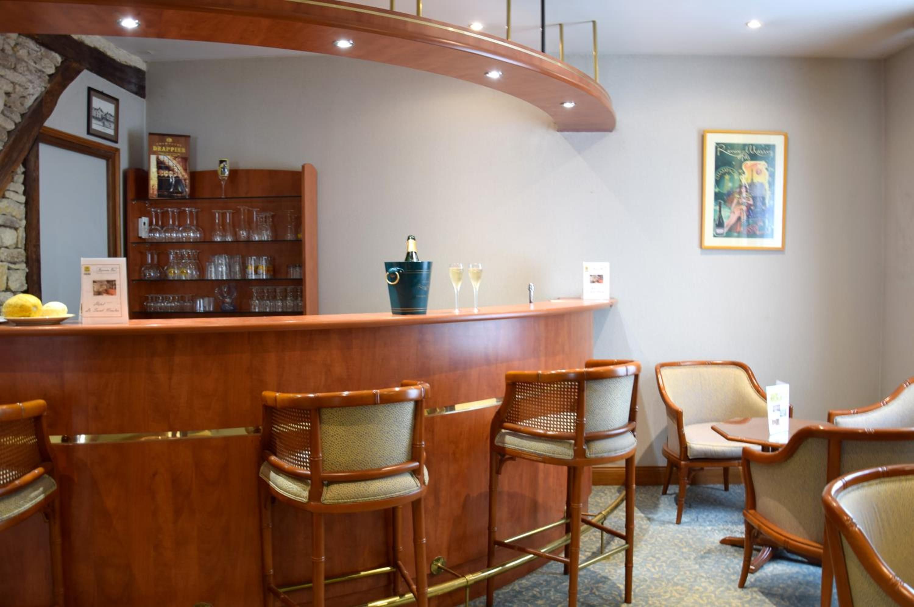A bar area with wooden chairs, a counter with a wine bottle, and a framed picture on the wall.