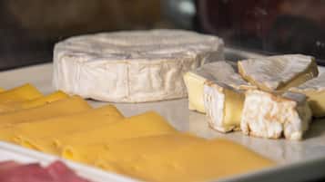 A variety of cheeses on a plate, including a round cheese and several slices.